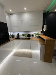 a kitchen with white cabinets and a wooden counter top at Komfort House apartament z tarasem in Ełk