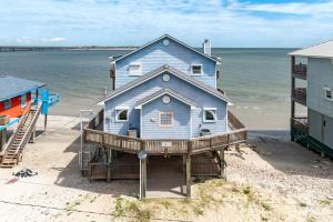 a blue house on the beach next to the water at Atlantis - Oceanfront Seating at its Finest! in Freeport