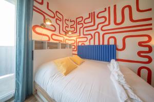 a bedroom with a bed with a red and white patterned wall at Magnifique Studio Illzach Centre in Illzach