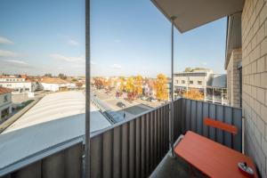 a red bench on a balcony with a view of a city at Magnifique Studio Illzach Centre in Illzach