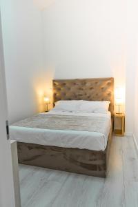 een bed in een witte kamer met 2 lampen bij Apartments Lukas 5 in Zadar