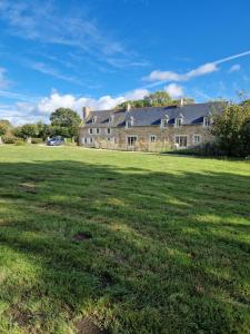 un gran campo de césped frente a una casa grande en A l'abri des marées - Maison de charme dans le parc du Domaine du Cloitre, en Pléneuf-Val-André