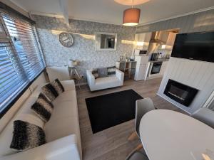 a living room with a white couch and a fireplace at Holidayz, Chalet 58, Hemsby - Beautifully presented two bed chalet, sleeps 4 with FREE Wi-Fi plus pet friendly in Hemsby +8 photos