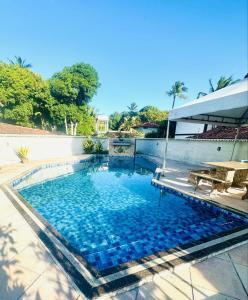 a large swimming pool with blue water at Casa na orla in Porto Seguro