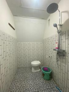 a bathroom with a toilet and a green bucket at Roman Homestay syariah in Sembalun Lawang
