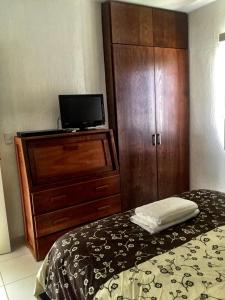 1 dormitorio con 1 cama y vestidor con TV en Mango 78, en Playa del Carmen