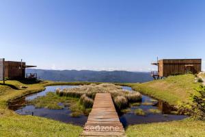 a wooden bridge over a river in a field at Linda cabana com jacuzzi e vista incrível VST004 in São Paulo dos Pinhais