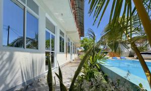 a house with a swimming pool and palm trees at Zanzibar Lodge in Kiwengwa