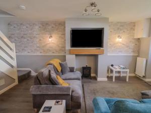 un salon avec un canapé et une télévision à écran plat dans l'établissement Rushmoor Cottage, à Colaton Raleigh