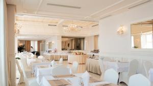 a dining room with white tables and white chairs at Palace Hotel & SPA in Durrës