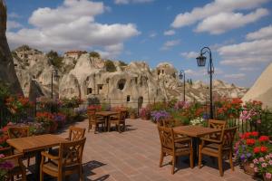 a patio with wooden tables and chairs and flowers at Rose Moon Cave in Macun Çiftliği