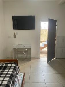 a room with a table and a television on the wall at JK térreo Zona Norte in Porto Alegre