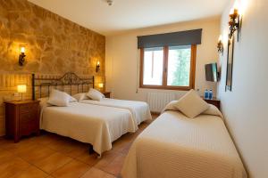 a bedroom with three beds and a window at Hostal Todolella in Todolella