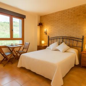 a bedroom with a bed and a table and a window at Hostal Todolella in Todolella