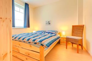 a bedroom with a bed and a chair and a window at Ferienhaus LampRieger, Fewo Parter in Wieck