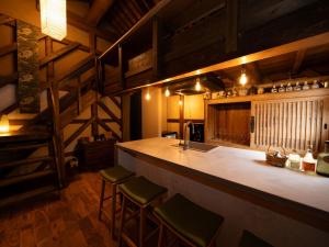 a kitchen with a bar with stools and a sink at 3000平米の元醤油名家邸宅, 日本庭園, 蔵Bar, サウナ, 出張料理, フルサービスの宿 in Shodoshima +25 photos