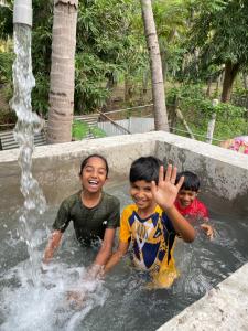 three children playing in a fountain in a pool at Srirangam Heritage Farmhouse - Perfect Spot for Parties & Events in Tiruchchirāppalli