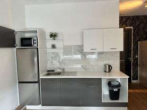 a kitchen with white cabinets and a stainless steel refrigerator at B&B Santorini Maasbree in Maasbree