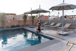 a woman sitting on the edge of a swimming pool at Riad Les Oliviers & Spa in Marrakesh +52 photos