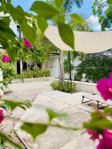 a garden with a bench and pink flowers at Casa Lluavi - Caliope in Mérida