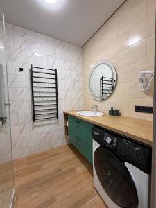 ein Badezimmer mit Waschbecken und Waschmaschine in der Unterkunft Apartments on Sennaya Street in Mykolajiw