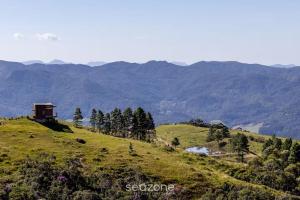 a house on a hill with mountains in the background at Refúgio na Serra c/ Vista Linda VST016 in São Paulo dos Pinhais