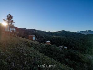 a house on top of a hill with the sun setting at Refúgio na Serra c/ Vista Linda VST016 in São Paulo dos Pinhais