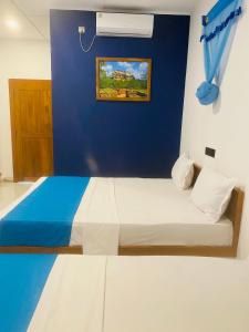 a bedroom with a bed with a blue wall at Hotel Hanguk Villa in Dambulla