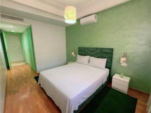Un dormitorio con una cama blanca y una pared verde. en Ibiz Appartement, en Casablanca