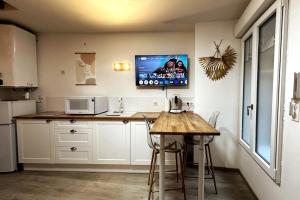 Una cocina con una mesa y un televisor en la pared. en Le petit Cocon, en Nevers 12 fotos más