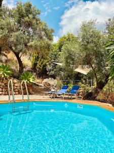 Una piscina con dos sillas y una mesa y árboles. en Casa Blanca y Azul, en Almogía