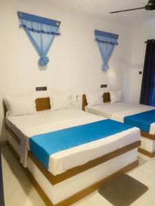 two beds in a room with blue curtains at Hotel Hanguk Villa in Dambulla