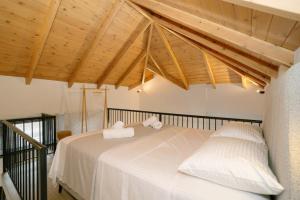 een groot wit bed in een kamer met houten plafonds bij RoDous Luxury Apartments Preveza in Preveza