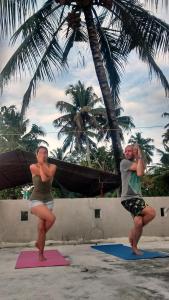 two people are doing yoga on the beach at Kalappura Homestay in Alleppey