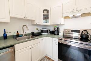 eine Küche mit weißen Schränken und einer Spüle in der Unterkunft Entire 1 Bdrm house 5 mins from NWMC and DwnTwn in Saint Albans