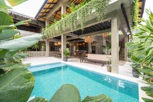 an outdoor swimming pool with a house with plants at Anantha Wellness Sanctuary in General Luna