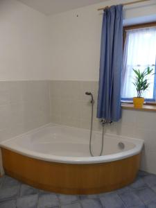 a bath tub in a bathroom with a blue curtain at Ferienwohnung Max Fegg in Anger