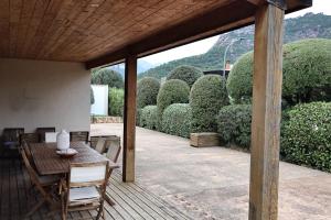 une terrasse en bois avec une table, des chaises et des buissons dans l'établissement Villa Lili Rose - Jacuzzi et Rivière à 3 min à pieds, à Zonza