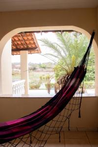 a hammock in front of a window with a palm tree at Hotel Fazenda Moinho in Esmeraldas +8 photos