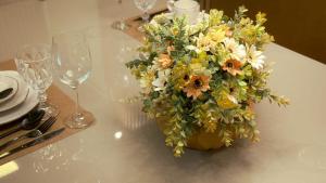 a vase of flowers on a table with wine glasses at Apartamento com aconchego e modernidade Apogeo in Ribeirão Preto