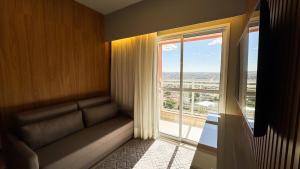 a room with a couch and a large window at Apartamento com aconchego e modernidade in Ribeirão Preto