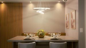 a dining room with a table with glasses and flowers at Apartamento com aconchego e modernidade in Ribeirão Preto