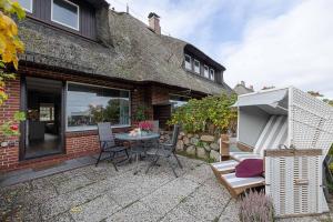 a patio with a table and chairs and an umbrella at Haus Wattblick EG in Braderup