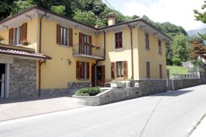 una casa amarilla al lado de una carretera en Bed and Breakfast Luna en San Giovanni Bianco