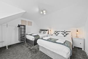 two beds in a room with white walls at Comfortable 4 Bedroom Apartment - Hawick in Hawick