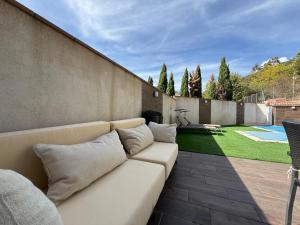 a white couch sitting on a patio next to a wall at Acogedor chalet con jardín ideal para desconectar in Sotillo de la Adrada