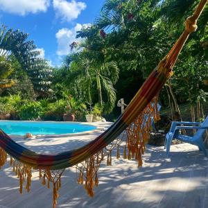 a hammock on a patio next to a pool at Villa confortable à Les Trois-Îlets avec piscine privée in Lazaret