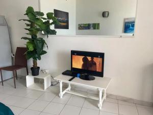 a tv sitting on a white table in a living room at Studio charmant aux Trois-Îlets avec vue mer in Lazaret