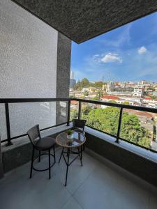 a balcony with a table and chairs and a view at RUA PLANA, 2qts, 2 banh, VARANDA c CHURRASQUEIRA, estacionamento, ELEVADOR, portaria in São Lourenço