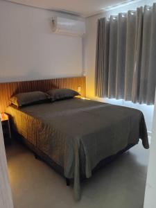 a bedroom with a large bed with a window at RUA PLANA, 2qts, 2 banh, VARANDA c CHURRASQUEIRA, estacionamento, ELEVADOR, portaria in São Lourenço +19 photos